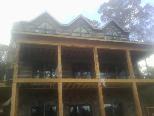 Dormers and porch framing on a large log home under construction — Roof Coating work by our crew in Crawfordville