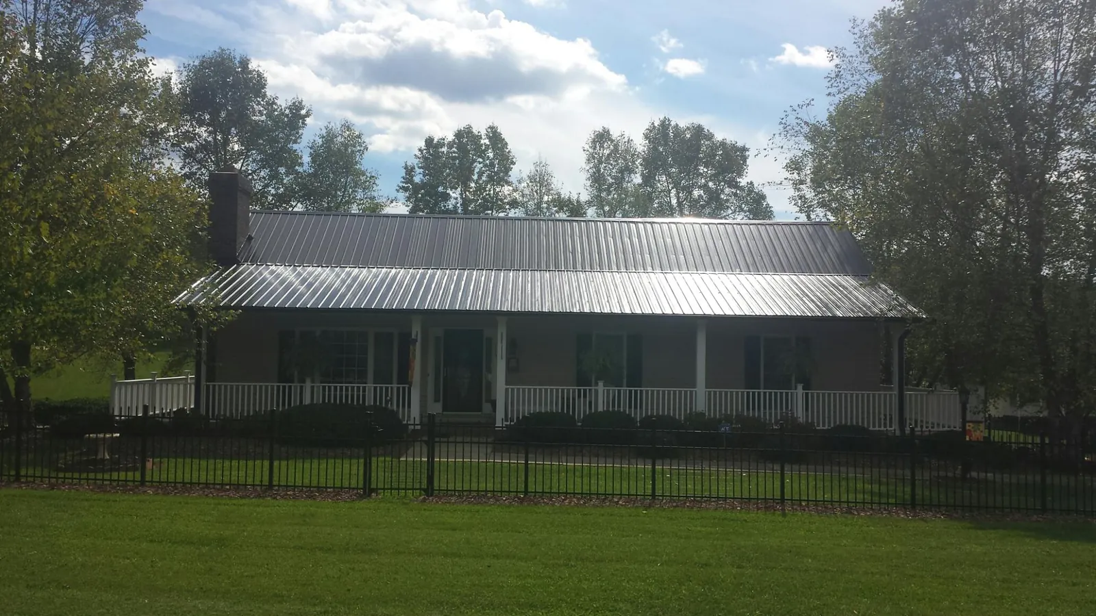 Gray metal roof on a brick ranch with a full width front porch — Gutter Guard Installation work by our crew in Crawfordville