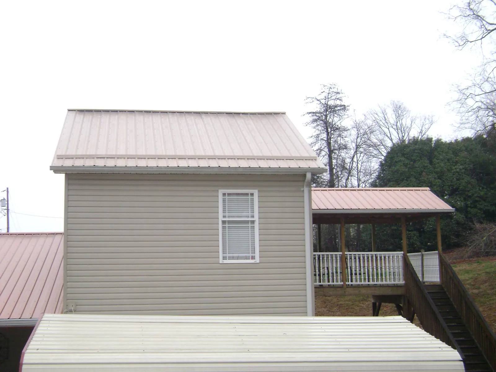 Tan metal roofs on a two story addition and attached porch, from a Roof Replacement job in Crawfordville