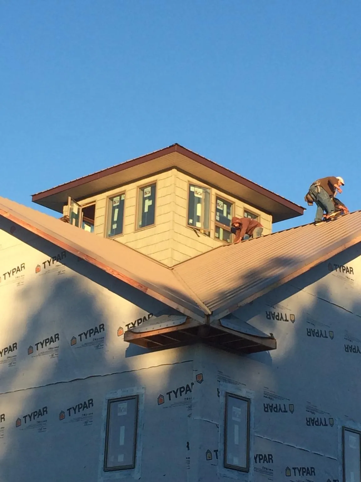 Roofers working around a rooftop cupola on a new metal roof at sunset — Roof Waterproofing in Crawfordville by Roofing Brothers